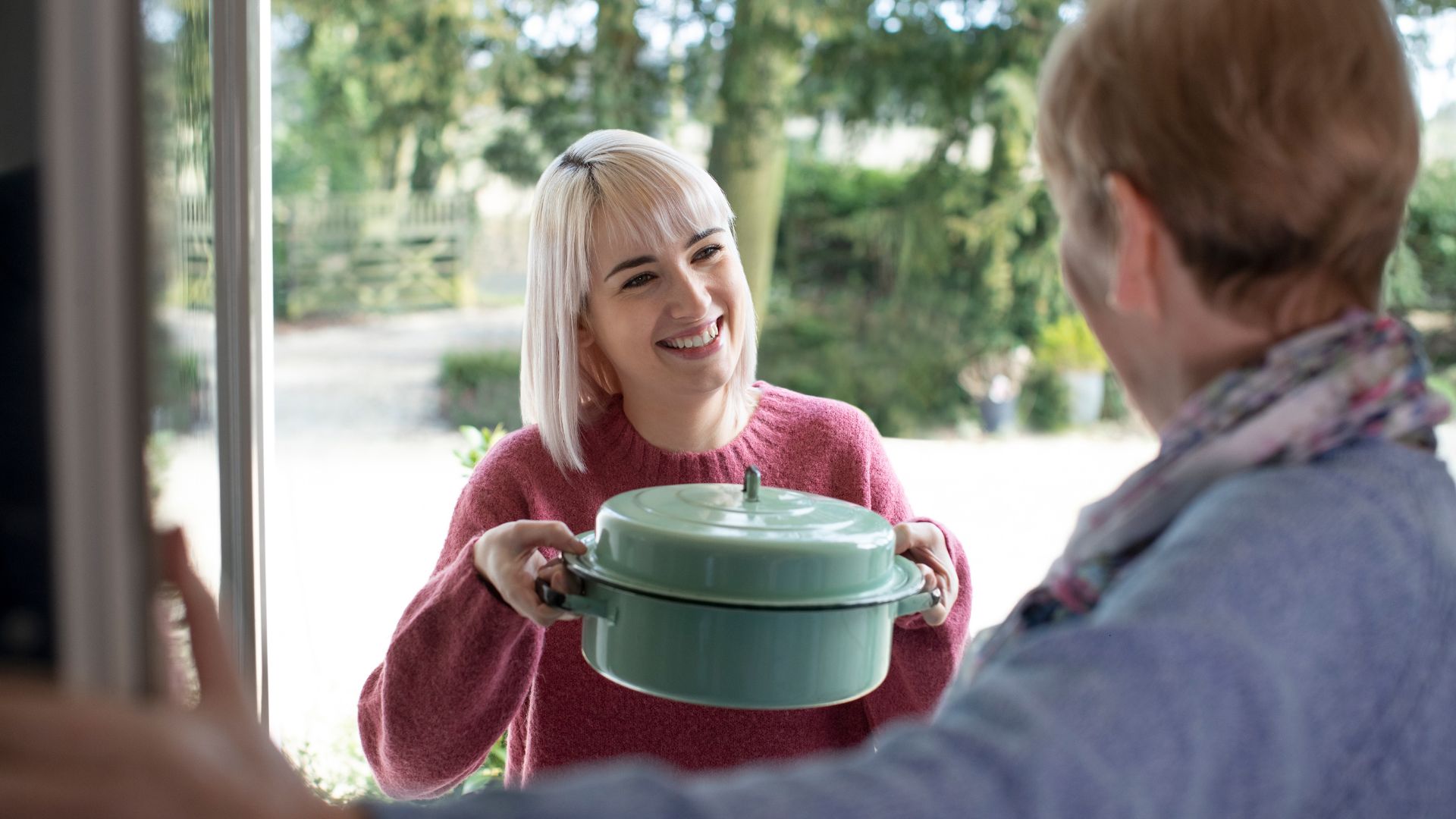 woman bringing elderly neighbour soup