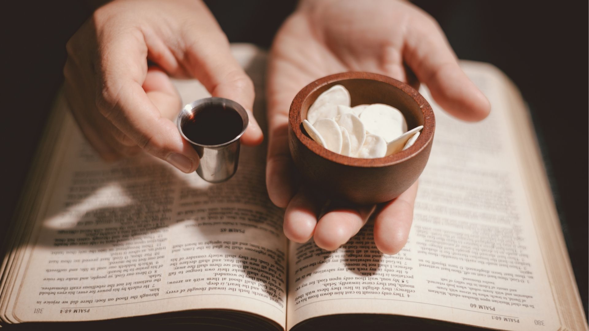 person holding bread and wine over a bible