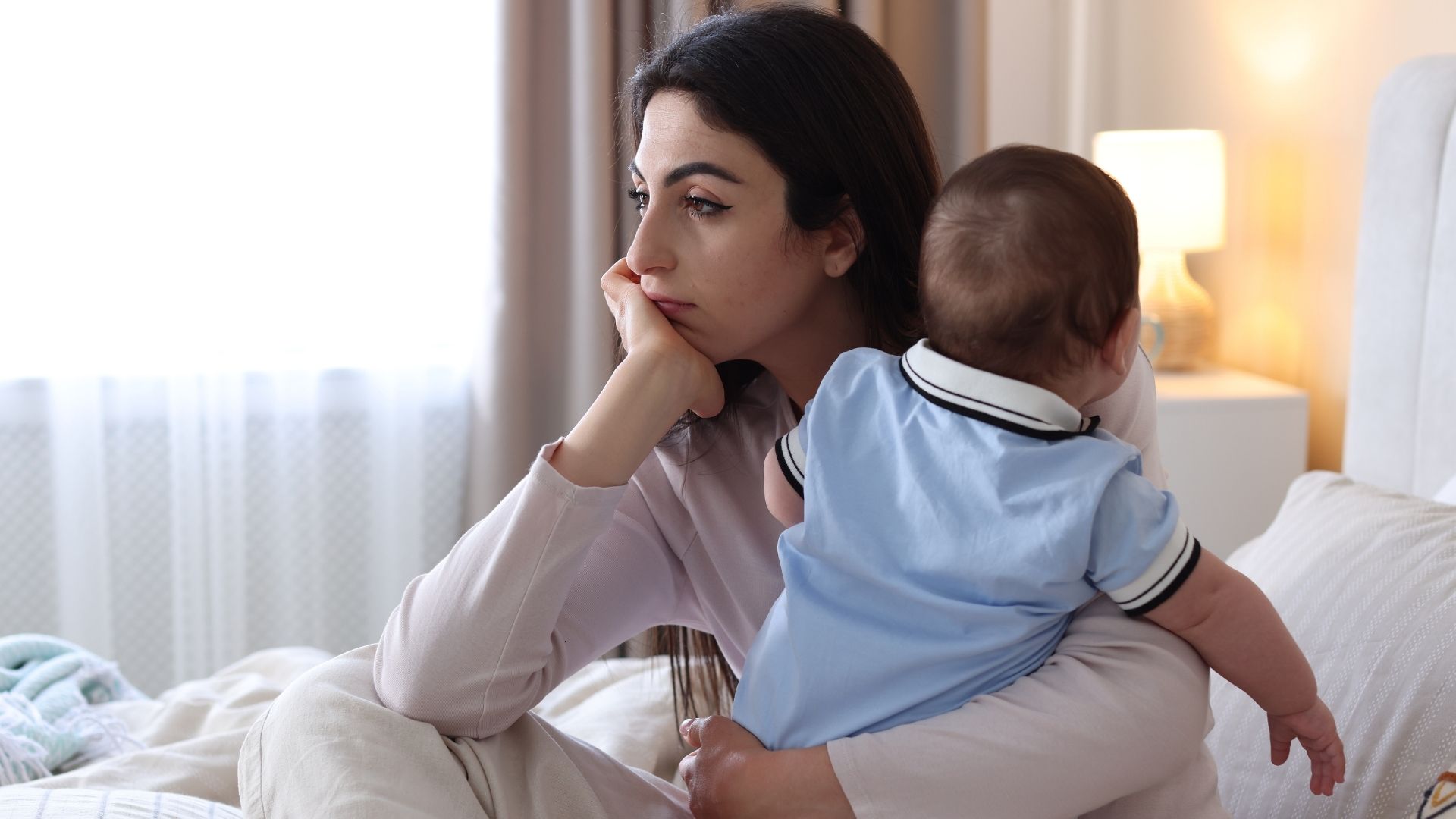 woman holding baby looking sad